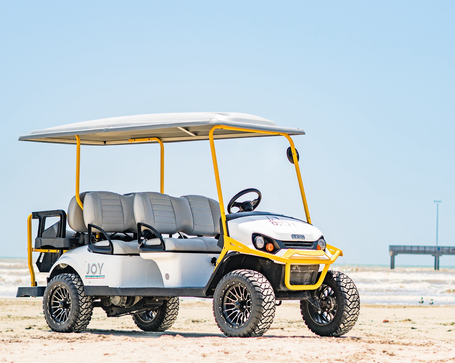 Joy six-passenger cart on Port Aransas beach with Horace Caldwell Pier in distance